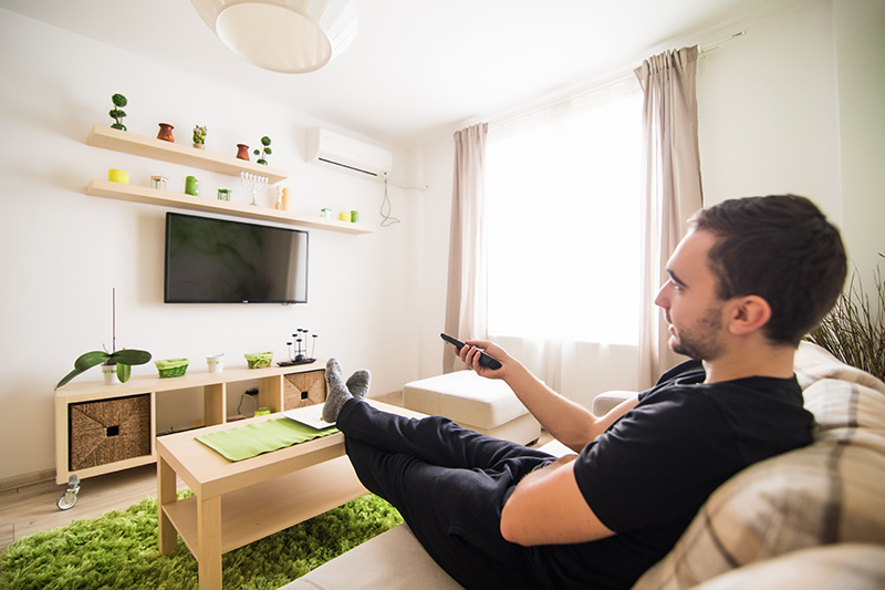 Single man on the couch watching tv, changing channels